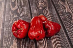 Three red peppers on a wooden table photo