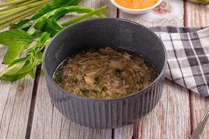 A bowl of soup with a spoon and some asparagus photo
