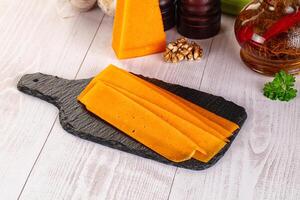 A cutting board with cheese slices on it photo