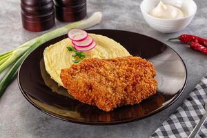 A plate with a fried chicken, mashed potatoes and a side of onions photo