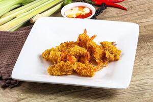 A plate of fried shrimp on a table with some vegetables photo