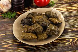 A plate of green olives and garlic on a wooden table photo