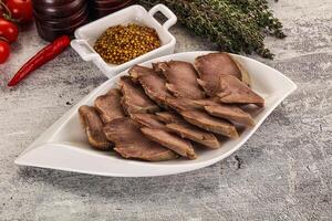 Sliced beef on a white plate with spices and other ingredients photo