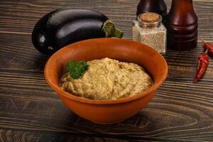 A bowl of eggplant dip with spices and a bottle of wine photo