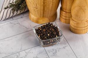 A glass container with pepper and spices on a marble counter photo