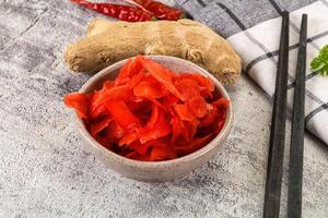 A bowl of red peppers and chopsticks on a table photo