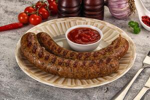 A plate with two sausages and a tomato sauce photo