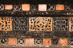 Close-Up View of Ancient Grunge Weathered Wall Tiles With Floral Etchings and Dark Background. photo