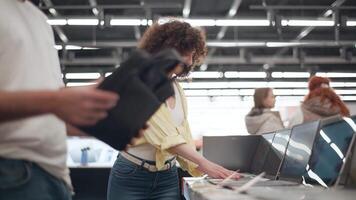 Young loving couple shopping for laptop bag in electronics store, carefully testing selected bag with modern laptop while sharing moment of togetherness in slow motion video