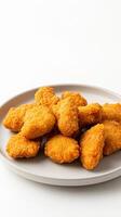 A plate of chicken nuggets sitting on a white surface photo