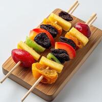 A wooden board with fruit skewers on it photo