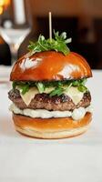 A hamburger with cheese and a pickle on a table photo