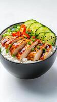 A bowl of rice with chicken, cucumbers and green onions photo