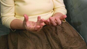 a grandmother with disabilities develops her hands after a stroke. An elderly retired woman is doing a massage with arthritic hands. video