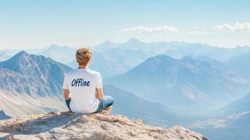 A person in an Offline T-shirt relaxes on a rock, enjoying the peaceful morning light and mountains photo
