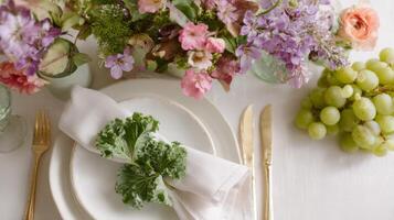 Stylish wedding table adorned with edible flowers, grapes, kale, and vintage cutlery in a garden setting photo