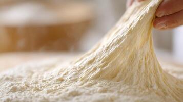 Dough is being stretched, revealing gluten strands in a cozy baking environment photo