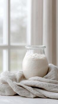 Sourdough starter rises in a glass jar, capturing natural light and creating a rustic baking atmosphere photo