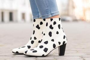 Women showcase trendy ankle boots with a cow skin design while standing outdoors on a bright day photo