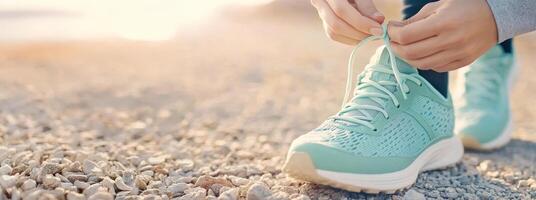 Focused hands prepare for a run by tying bright sneakers on a gravel path, highlighting preparation for outdoor fitness photo
