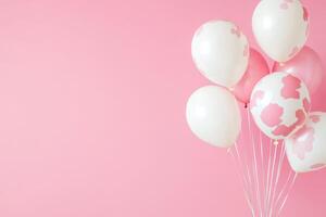 A cheerful set of cow-print balloons pops against a soft pink background, perfect for parties photo