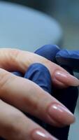 Nail Polish Application. Close-up of a manicurist applying a thin layer of nude nail polish to a client's fingernail. The meticulous brushstrokes highlight the delicate process of nail art. video