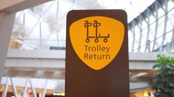 Sign indicating trolley return in busy airport terminal video