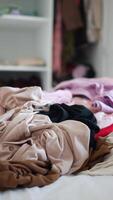 Sorting through a pile of clothes in a cluttered bedroom setting video