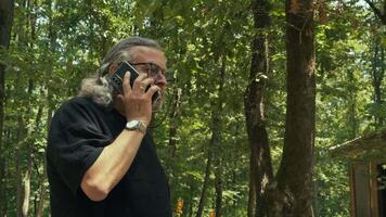 Elderly Old Man is Talking to Cellphone While He is Walking in Nature video