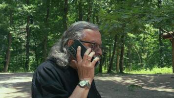 Senior Old Man is Talking to Cellphone While He is Walking in Nature video