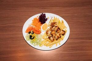 Turkish kebab plate with fries, vegetables and chicken. Delicious freshly prepared meal, perfect for menus, restaurants, or food delivery concepts. photo