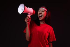 Portrait of Young Asian Woman with Megaphone Wearing Red Outfit, Indonesian Independence Day Concept Smiling Isolated photo