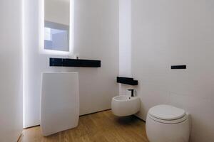 A bathroom that includes a sink, toilet, bidet, and a mirror present photo