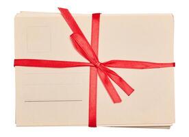 A stack of blank postcards tied with a red ribbon and bow, isolated background. photo