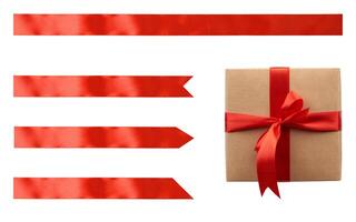 Kraft paper gift box tied with red satin ribbon with bow and set of red ribbons of different shapes on isolated background photo