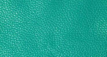 A close up full frame view of a vibrant teal colored leather texture, showcasing its natural grain photo