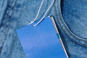 Light blue denim jeans with a blank blue price tag attached to the belt loop. photo