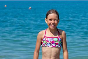 Caucasian happy and smiling child of 8 9 years going to swim in blue sea looking at camera photo