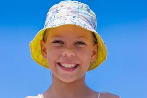 Caucasian smiling child of 8 9 years in a sun hat on clear blue sky looking at camera photo