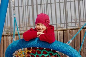Child of 8 9 years swinging on round seesaw looking at camera photo