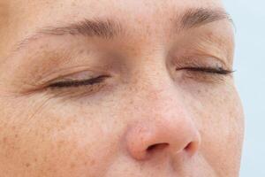 Close up of woman face with closed eyes showing natural skin and wrinkles around the eyes photo