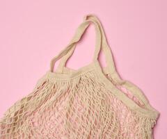Empty reusable cotton mesh bag on pink background photo
