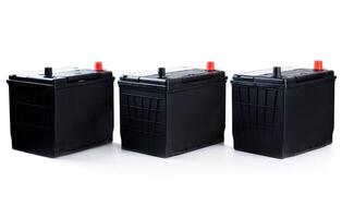 Three identical black car batteries in a row on white background. Isolated automotive parts for passenger vehicle repair, catalog, or store use. photo