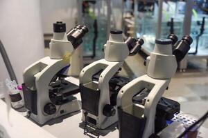 Three modern microscopes in a bright laboratory setting in Singapore, showcasing scientific research and technological precision. photo