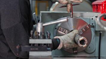 Worker installs metal part into lathe chuck, manual setup in machine shop, Precision alignment ensures secure clamping for accurate turning operations video