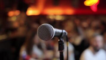 fermer de microphone sur étape avec flou public arrière-plan, un événement installer pour Publique Parlant, conférence ou performance dans chaud ambiant éclairage video