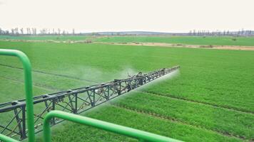 Close-up view of sprayer boom spraying young wheat field, high-tech farming solution, Precision nozzle system distributes chemicals across green crop rows video