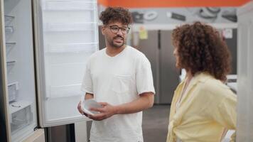 Couple choosing refrigerator in electronics store in slow motion video
