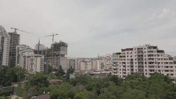Urban skyline with residential high-rises and cranes at active construction site under cloudy sky, modern city development and architectural growth symbolizing urban expansion and housing boom video