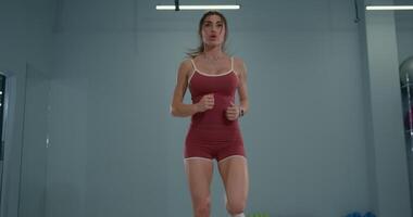 Girl athlete performing butt kicks indoors during a training session focused on improving athleticism and agility video
